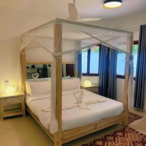 a bedroom with a canopy bed with white pillows at Jumeirah Malindi Hotel in Malindi