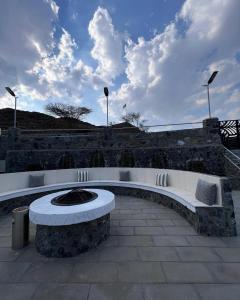 a seating area with a stone wall and clouds in the sky at Hatta valley Farmstay & activities & families in Hatta