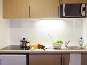 a kitchen counter with a sink and a microwave at Aparthotel Adagio Access Saint Louis Bâle in Saint-Louis +40 photos