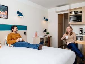 a man and woman sitting in a hotel room with cups of coffee at Aparthotel Adagio Access Marseille Prado Périer in Marseille