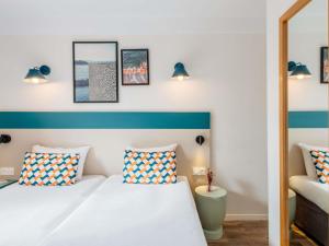 マルセイユにあるアパートホテル アダージョ アクセス マルセイユ プラド ペリエのベッドが2つと鏡があるホテルの部屋