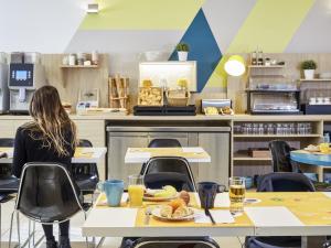 a woman sitting at a table with a plate of food at Aparthotel Adagio Access Marseille Saint Charles in Marseille
