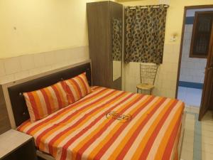 钦奈sam galaxy guest house的一间卧室配有带条纹被子的床