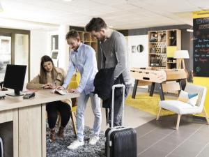 two men and a woman at a desk with a suitcase at Aparthotel Adagio Access Strasbourg Petite France in Strasbourg