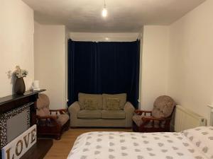 a bedroom with a bed and a couch and chairs at One Bed apartment -East London in London