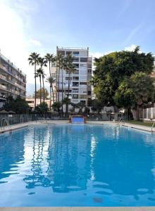 a large blue swimming pool with palm trees and buildings at Apartamento Pepita Alay in Benalmádena