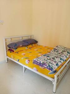a bedroom with a bed with a yellow comforter at Roomstay Cheq Ayoh Pantai Penarik Setiu in Kampong Ru Sepuloh