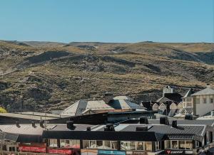 eine Gruppe von Gebäuden mit einem Berg im Hintergrund in der Unterkunft SKI & SNOW APARTMENTS - PLAZA DE PRADOLLANO - Junto a los Telecabinas by TODOSIERRANEVADA in Sierra Nevada