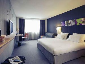 a hotel room with a large bed and a desk at Mercure Valenciennes Centre in Valenciennes