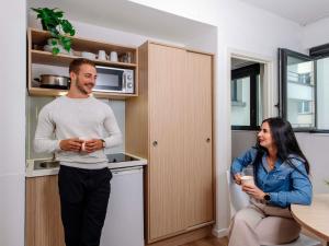 un hombre y una mujer de pie en una cocina en Aparthotel Adagio Access Bruxelles Europe Aparthotel, en Bruselas