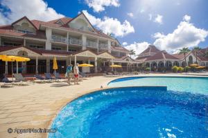 Zwei Personen gehen an einem Swimmingpool vor einem Hotel vorbei. in der Unterkunft Studio Saint Vincent 13 in Sainte-Luce