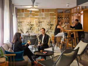 un groupe de personnes assises dans un bar avec des boissons dans l'établissement Mercure Paris Bastille Saint Antoine, à Paris
