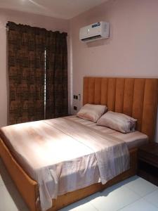 a bedroom with a large bed with a wooden headboard at Exclusive ANSO HOMES GRA Ikeja in Ikeja