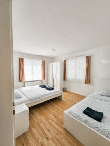 two beds in a room with wooden floors and windows at VK - VBD - Zürich Airport - Homestay - Villa Bassersdorf in Bassersdorf