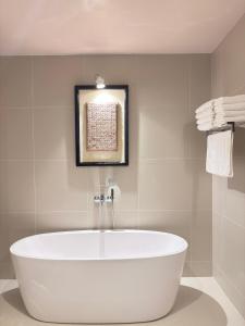 a white tub in a bathroom with a picture on the wall at Casa Tartaruga in Unawatuna