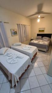 a room with three beds with white sheets at Vinte Park Hotel in Bragança Paulista