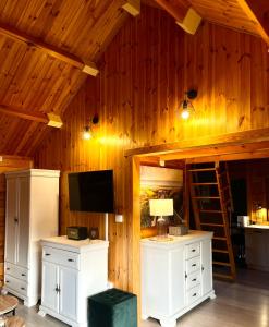 a room with white cabinets and a tv on a wooden wall at Domek wakacyjny "Sosnowy Zakątek" in Stegers