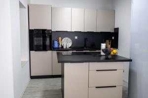 a kitchen with white cabinets and a black counter top at Una Riverside Heritage House in Bihać