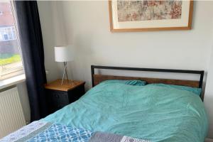 a bedroom with a bed with a blue comforter and a window at 3 bed semi detached house near Stourbridge in Stourbridge