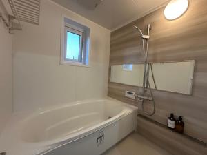a white bath tub in a bathroom with a window at Teine blue house手稻藍房子 in Sapporo +29 photos