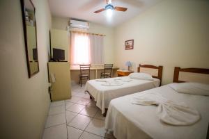 a hotel room with two beds and a table with chairs at Vinte Park Hotel in Bragança Paulista