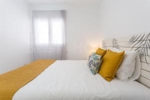 a bedroom with a bed with yellow and white pillows at Cozy Apartment in Salinetas Beach. in Salinetas