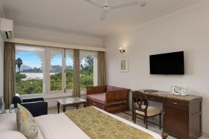 a hotel room with a bed and a desk and a television at Rampratap Palace by Fateh Collection in Udaipur