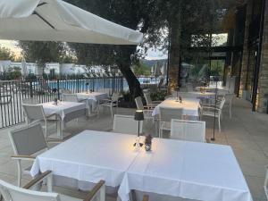 a row of tables and chairs with white tables and an umbrella at Solcio Village in Lesa +56 photos