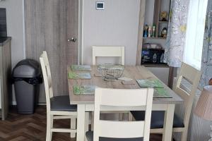 a dining room table with white chairs and a wooden table at Beautiful 3-Bed Lodge in kent in Kent +2 photos