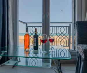 a glass table with wine bottles and glasses on a balcony at Airport Black Sea Hotel & Restaurant in Arnavutköy