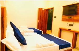 a bedroom with two beds and a flat screen tv at Aps inn munnar in Munnar