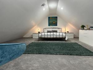 a attic bedroom with a bed and a green rug at Contemporary modern barn in Folkestone