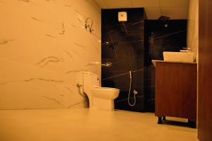 a bathroom with a toilet and a black wall at The Opal Hotel in Greater Noida