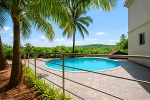 カラングートにあるPhase 369 Casa De Village North Goaの塀とヤシの木があるスイミングプール