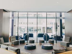 een lobby met stoelen en tafels en grote glazen ramen bij Novotel Newcastle Beach in Newcastle