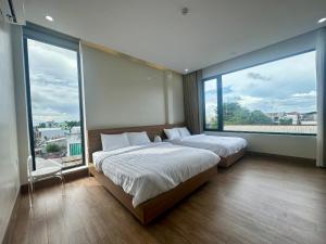 - 2 lits dans une chambre avec de grandes fenêtres dans l'établissement Núi Homestay Huế, à Hue