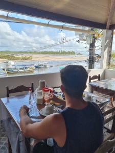 Ein Mann, der an einem Tisch mit Blick auf den Ozean sitzt in der Unterkunft Pousada Nativa - Ilha de Boipeba in Ilha de Boipeba + 18 Fotos