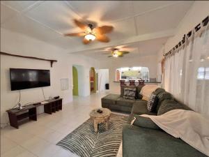 a living room with a couch and a flat screen tv at Maple cottage in Bridgetown