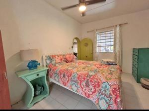 a bedroom with a bed with a green night stand and a green table at Maple cottage in Bridgetown