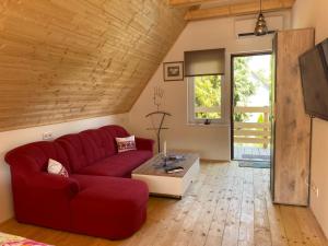 a living room with a red couch and a table at Müllers Ferienhäuser Gunaras & Harmonie in Gunaras in Dombóvár