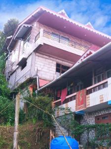 a house on a hill with a blue object in front of it at The Garden View Family Homestay in Takdāh