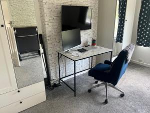 a room with a desk with a chair and a television at 4 BRD House, with Double Parking in Earley