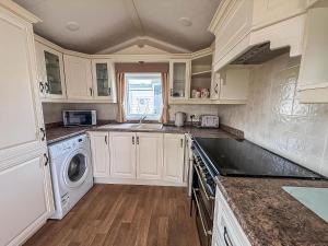 a kitchen with white cabinets and a washer and dryer at 6 Berth Caravan For Hire At California Cliffs In Scratby By The Beach Ref 50050L in Great Yarmouth