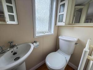 a bathroom with a toilet and a sink and a window at 6 Berth Caravan For Hire At California Cliffs In Scratby By The Beach Ref 50050L in Great Yarmouth +16 photos