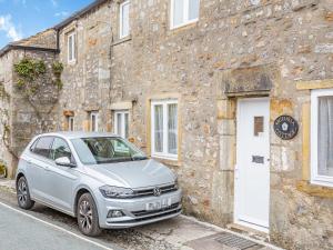 een zilveren auto geparkeerd voor een stenen gebouw bij Victoria Cottage in Kettlewell