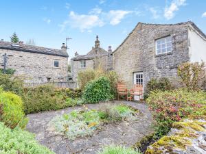 een oud stenen huis met een stoel in de tuin bij Victoria Cottage in Kettlewell