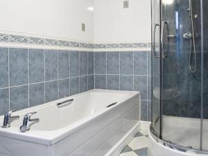 Una bañera blanca en un baño con ducha. en Ysgubor, en Harlech 7 fotos más