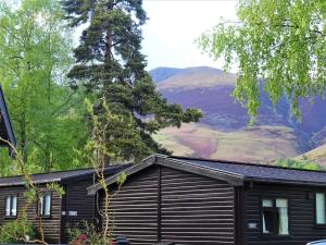 a black cabin with mountains in the background at Bewick Lodge in Keswick