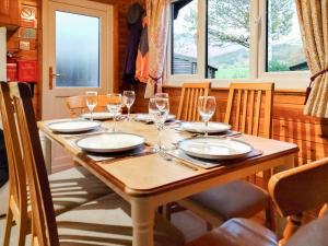 a wooden table with wine glasses and plates on it at Bewick Lodge in Keswick