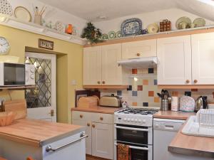 a kitchen with white cabinets and a stove top oven at Tom's Cottage in Dalton in Furness